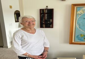 Mrs. Robbins stands next to a map of the world in her apartment at The Manor at York Town in Bucks County, PA.