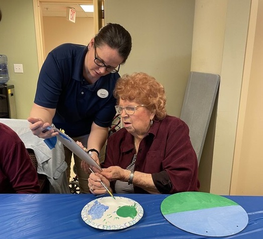 Sharon helps a resident during a crafting activity at The Manor at York Town in Bucks County, PA